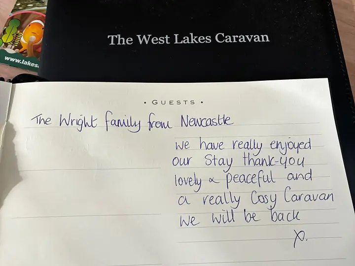 The guest book open on the table with a handwritten entry from a family from Newcastle.