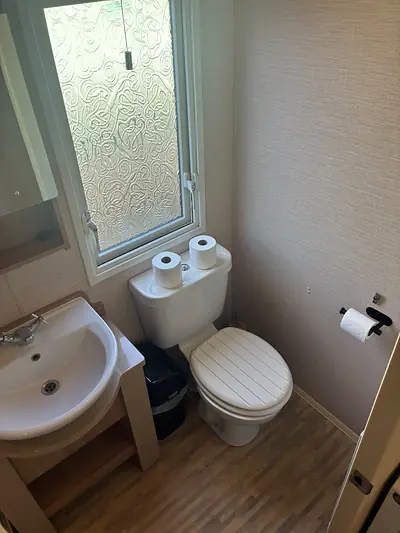 The separate WC in The Lake District Caravan with a basin and window.