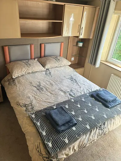 The double bedroom in The Lake District Caravan with an orange trimmed headboard.