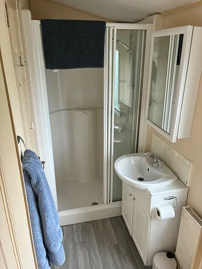 The shower room in The West Lakes Caravan with a corner shower cubicle and basin.