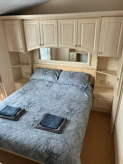 The double bedroom in The West Lakes Caravan with overhead lockers and a mirrored wardrobe.